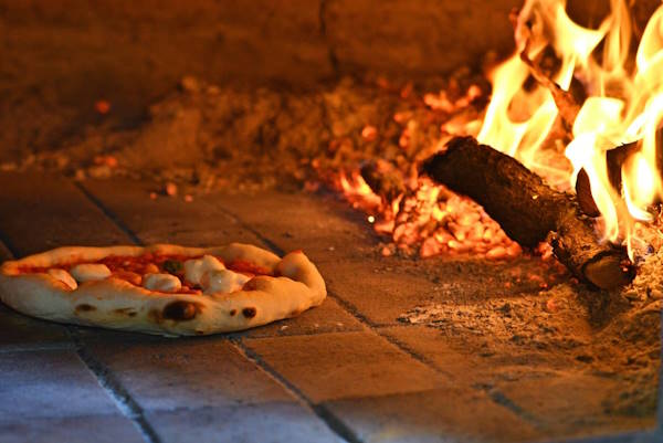 Horno a leña preparando pizzas